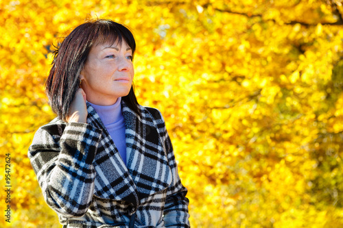 Cheerful fashion woman and warm clothes in autumn. Beautiful brunette with autumn coat. Gold autumn background