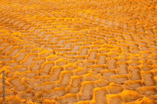 Ślady opon na żółtym piasku