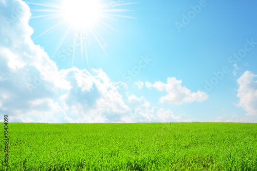 Bellissima collina verde con cielo azzurro, nuvole e sole splendente  photo