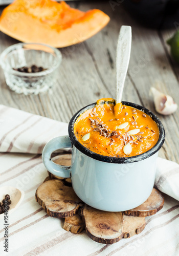 Autumn pumpkin soup in a blue mug, rustic background