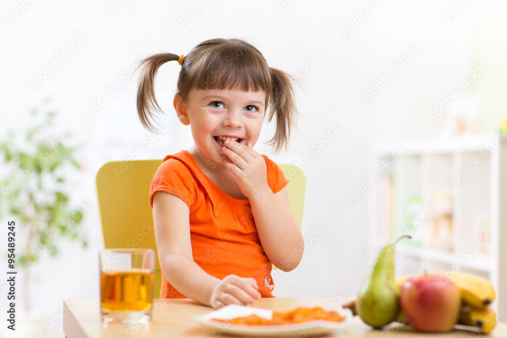 Smiling girl sitting on the table with fruits and juice Smiling girl sitting on the table with fruits and juice