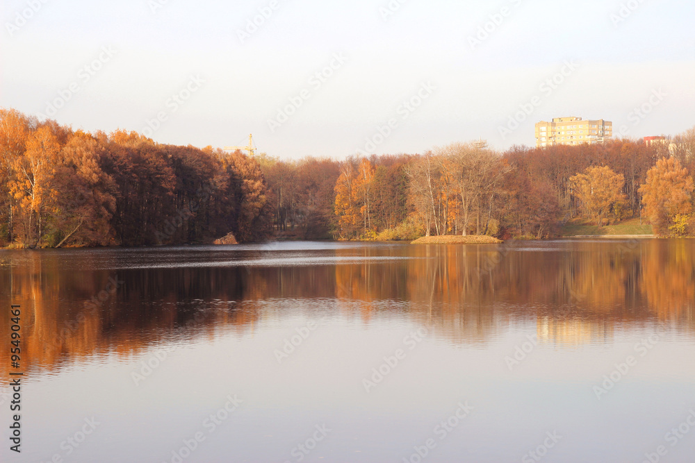 Obraz premium Beautiful autumn park. Autumn in Minsk. Autumn trees and leaves. Autumn Landscape.Park in Autumn. Mirror reflection of trees in water. Minsk city. Victory park in Minsk