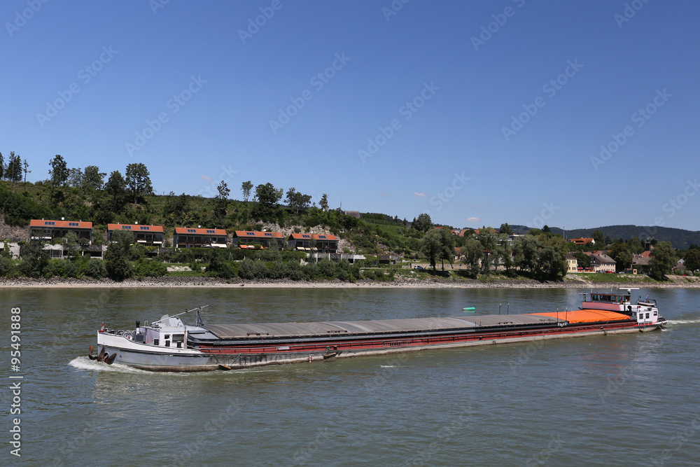 Obraz premium Cargo barge drifting on the river near the scenic shores