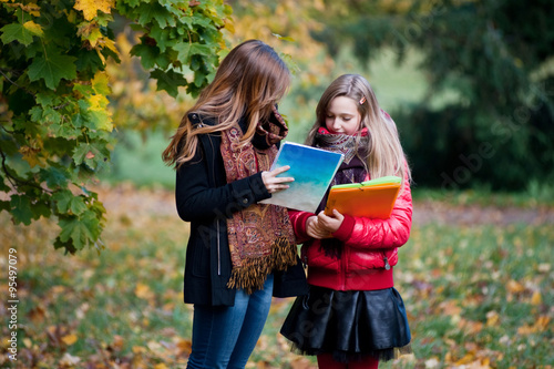Schoolgirls with notebooks discussing the task-2