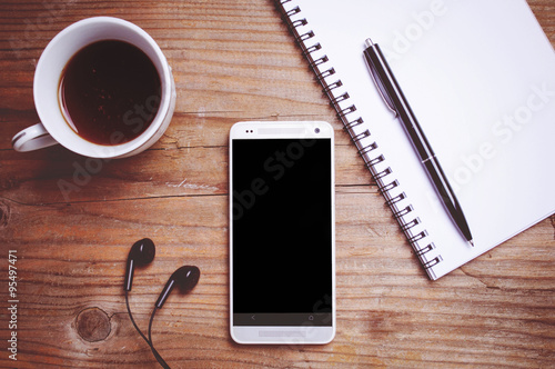 Relax workplace - Smartphone with blank screen, earphones, notebook and coffee on wooden background ( Space and composition for text )