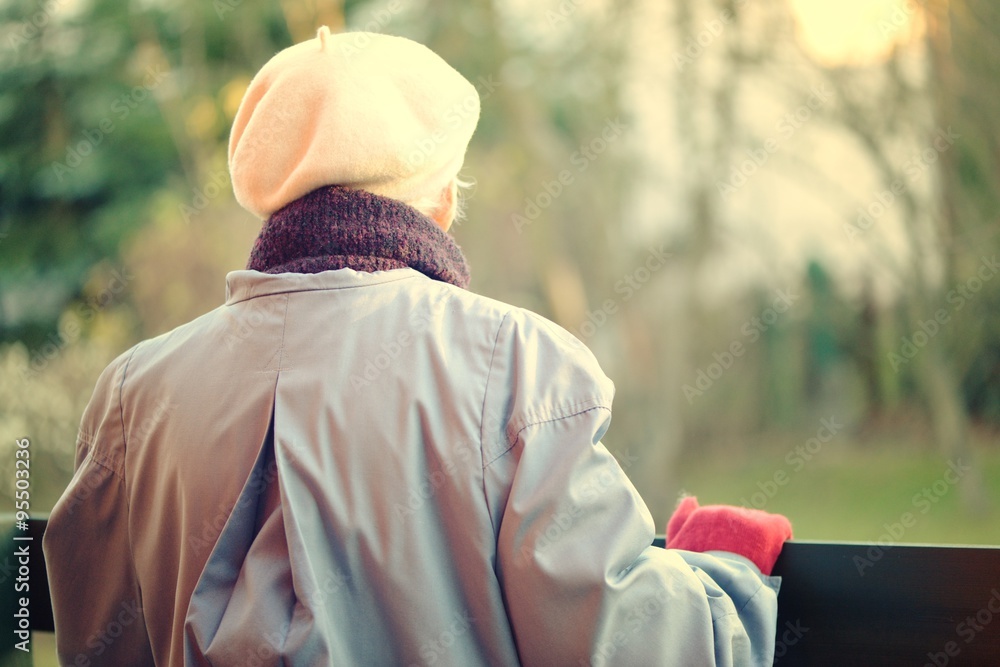 An elderly woman looks off into the distance. Rear view.