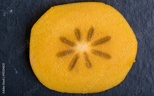 Slice of hurma fruit on black background photo