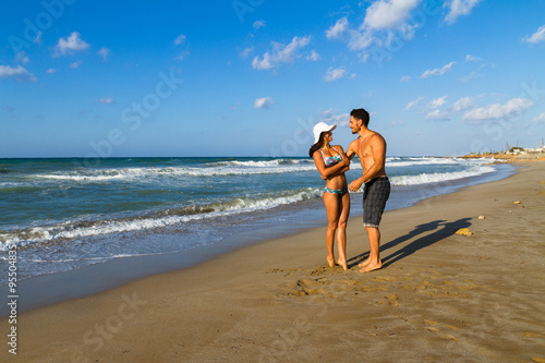 Attractive young couple in bikini and shorts at the beach.