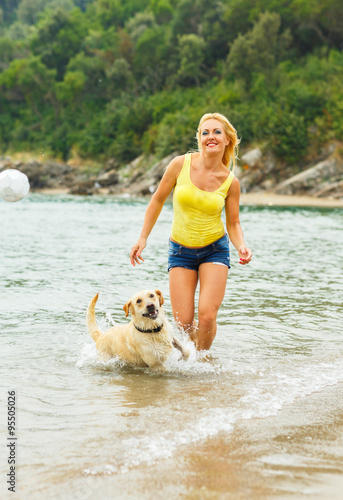 Woman with dog playing on the beach