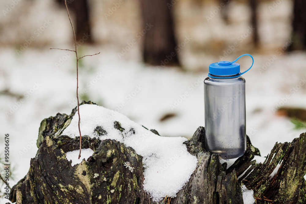 A bottle of cold water on wood with winter scene background A bottle of cold water on wood with winter scene background