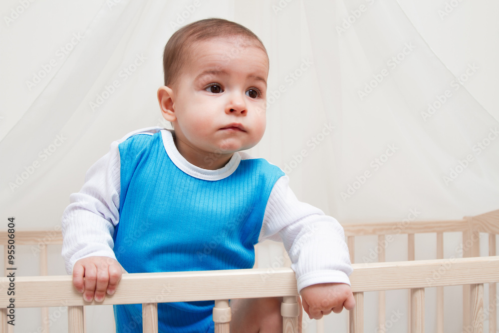 Beautiful baby in the bed on white background look at one side Beautiful baby in the bed on white background look at one side
