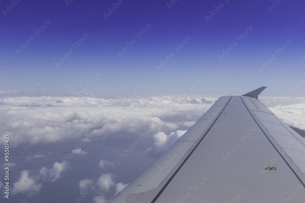 Obraz premium Wing of airplane above the clouds in the sky, view from window.