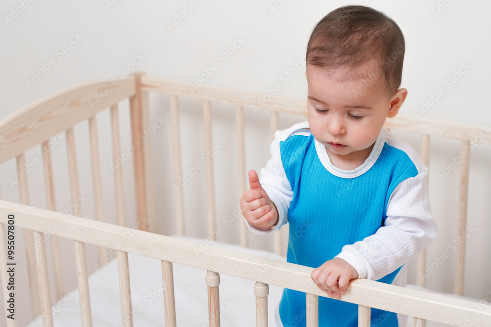 Beautiful adorable baby toddler with closed eyes in the bed on white background Beautiful adorable baby toddler with closed eyes in the bed on white background