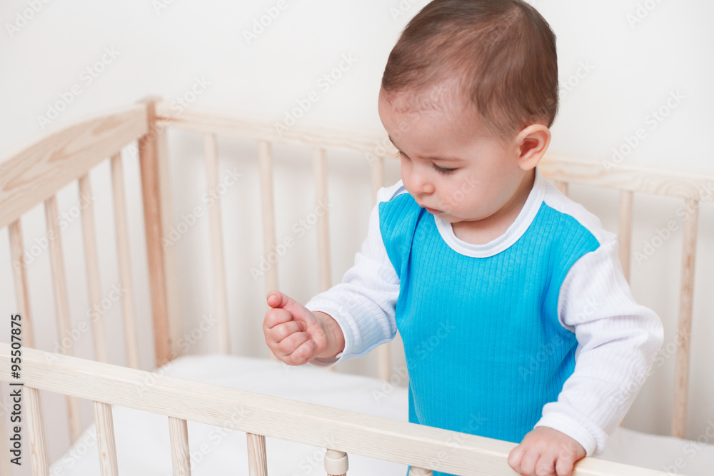Beautiful adorable baby toddler look at his/her hand in the bed on white background Beautiful adorable baby toddler look at his/her hand in the bed on white background