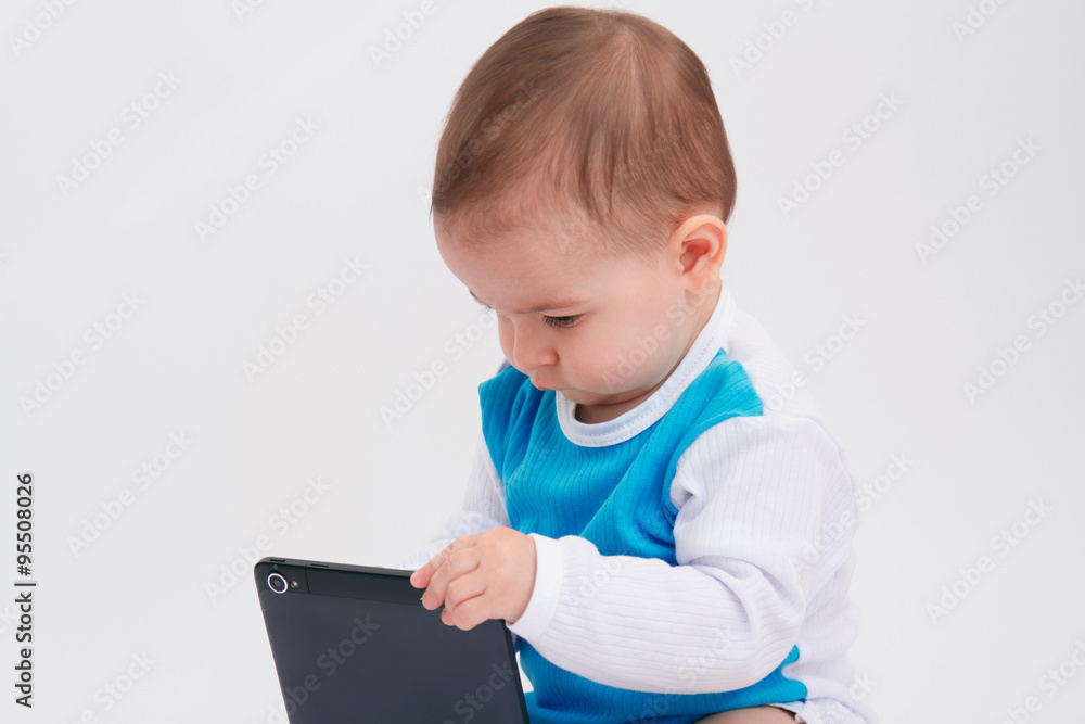 Adorable portrait of a baby toddler playing with a tablet on white background Adorable portrait of a baby toddler playing with a tablet on white background