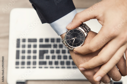 mano di uomo in ufficio con orologio al poloso e tastiera di notebook photo