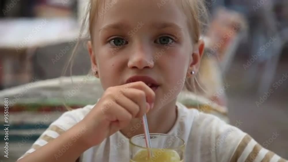 Cute little girl looking at camera and drinking juice Cute little girl looking at camera and drinking juice