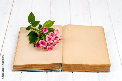 Roses on an old book on white wooden background. flowers