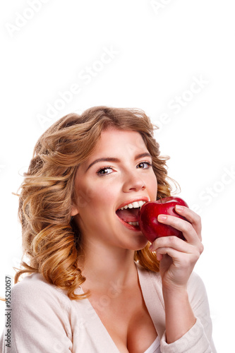Girl with curly hair biting a red apple.