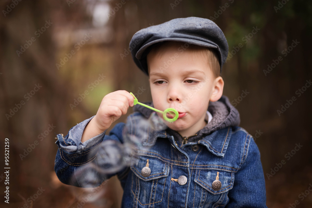 a little boy wearing a denim jacket blowing bubbles a little boy wearing a denim jacket blowing bubbles