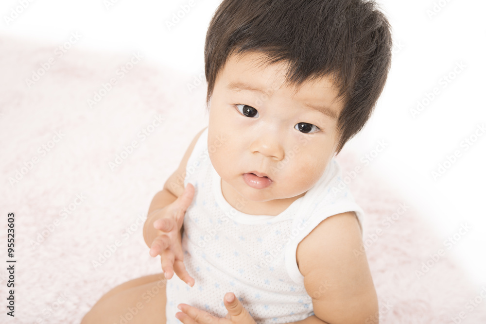 じゅうたんに座る肌着姿の赤ちゃん