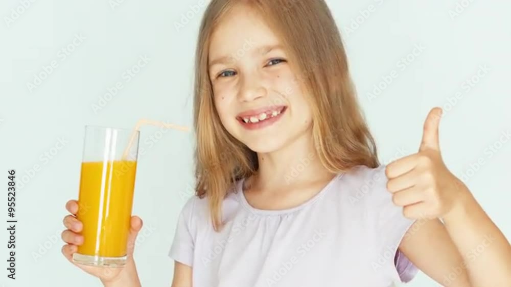 Girl holding glass of orange juice and laughing at camera. Girl with beautiful blonde hair on a white background. Thumb up. Ok. Closeup Girl holding glass of orange juice and laughing at camera. Girl with beautiful blonde hair on a white background. Thumb up. Ok. Closeup