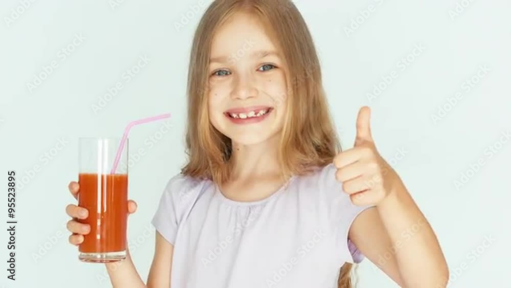 Girl holding glass of red orange mandarin juice. Girl with beautiful blond hair on a white background. Thumb up. Ok. Closeup Girl holding glass of red orange mandarin juice. Girl with beautiful blond hair on a white background. Thumb up. Ok. Closeup