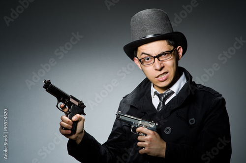 Criminal in black coat holding hadgun against gray