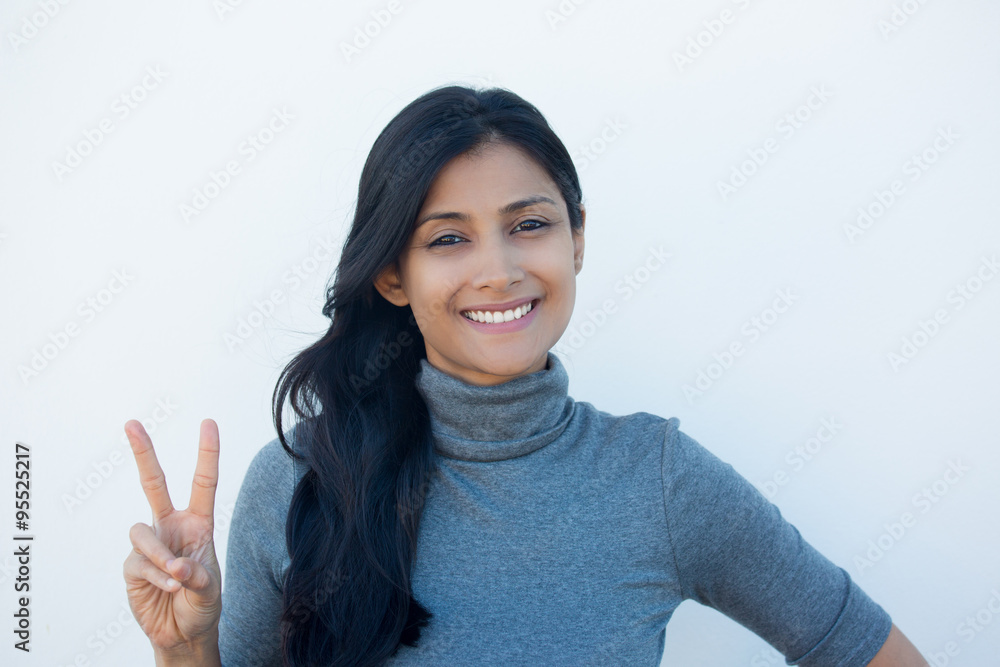 Closeup portrait, young, happy, smiling, confident, excited woman giving peace victory, two sign gesture, isolated white wall background. Positive emotion facial expression feelings symbols, attitude Closeup portrait, young, happy, smiling, confident, excited woman giving peace victory, two sign gesture, isolated white wall background. Positive emotion facial expression feelings symbols, attitude