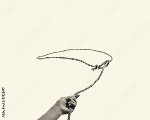 The hand throws a lasso on toned background photo