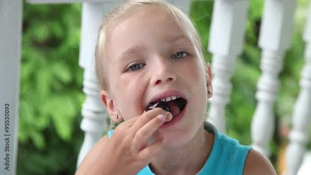 Girl putting a big cherry in her mouth and eating it Girl putting a big cherry in her mouth and eating it