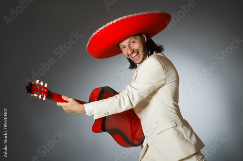 Funny mexican in suit holding guitar against gray photo