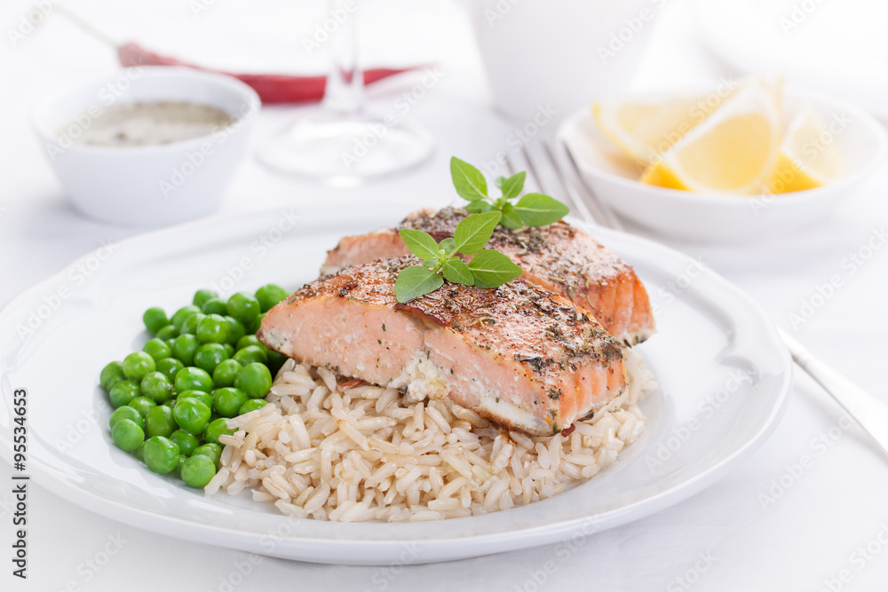 Baked salmon with rice, green peas and basil on a white ceramic plate on a white background.