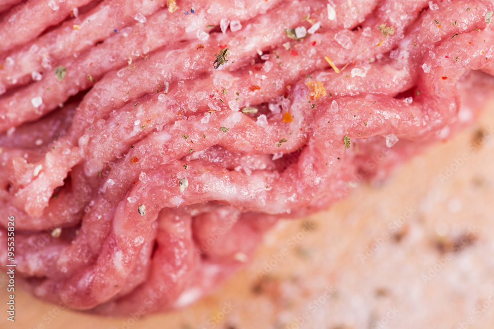 Minced meat with spices on wooden board. macro photo