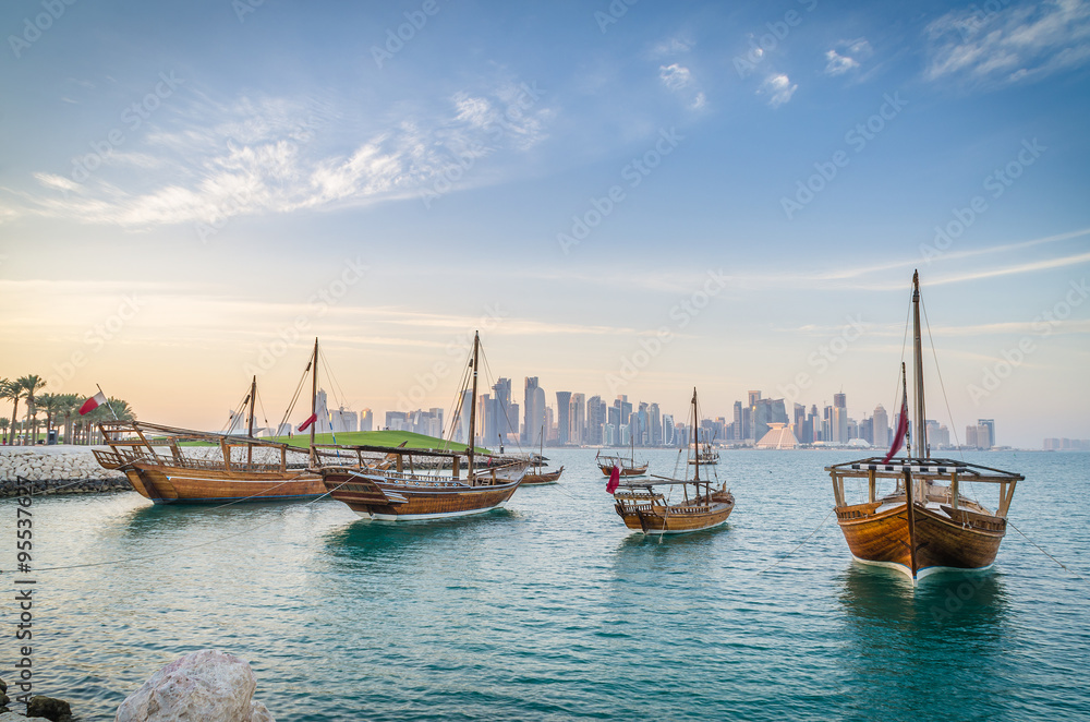 Fototapeta premium Dhows moored off Museum Park in central Doha, Qatar, Arabia, with some of the buildings from the city's commercial port in the background.