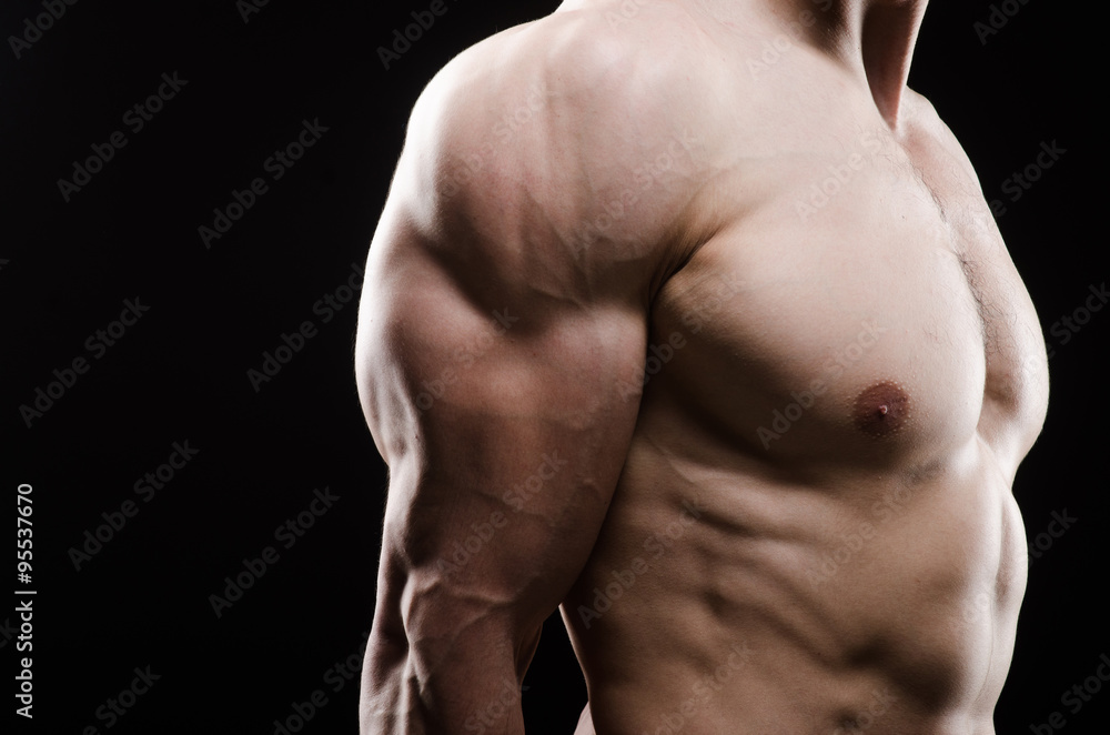 Muscular man posing in dark studio