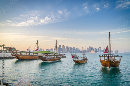 Dhows moored off Museum Park in central Doha, Qatar, Arabia, with some of the buildings from the city's commercial port in the background. photo