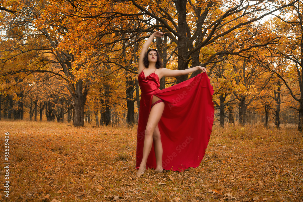 Girl in a red dress dancing in the autumn forest Girl in a red dress dancing in the autumn forest
