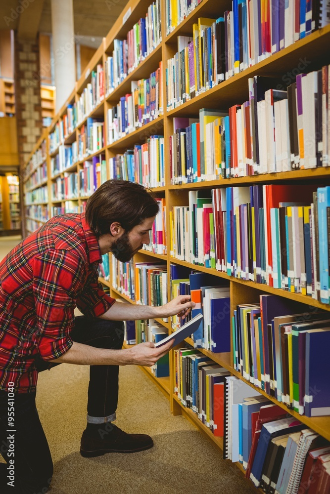 Student picking a book from shelf in library Student picking a book from shelf in library