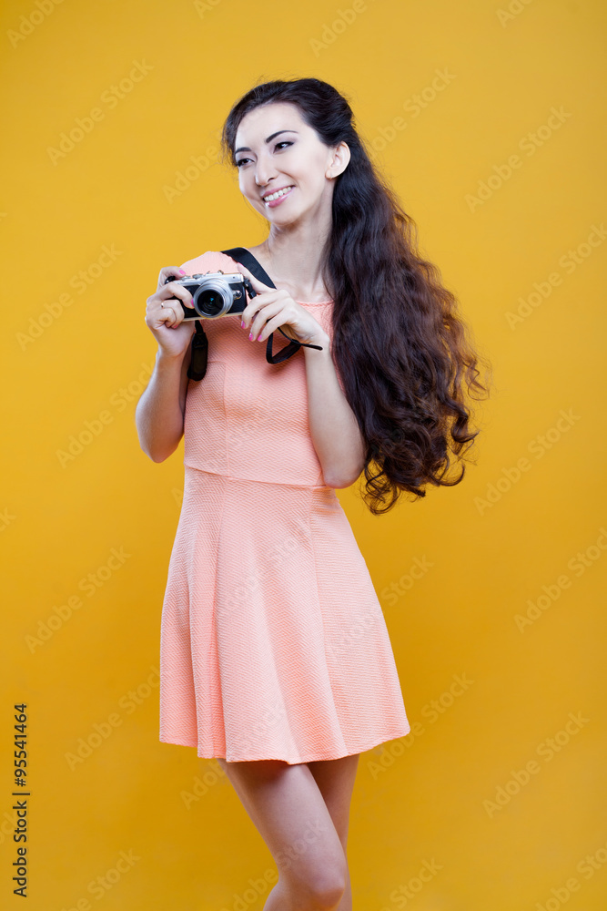 Fashion asian young  girl  photographer with camera, portrait on yellow background