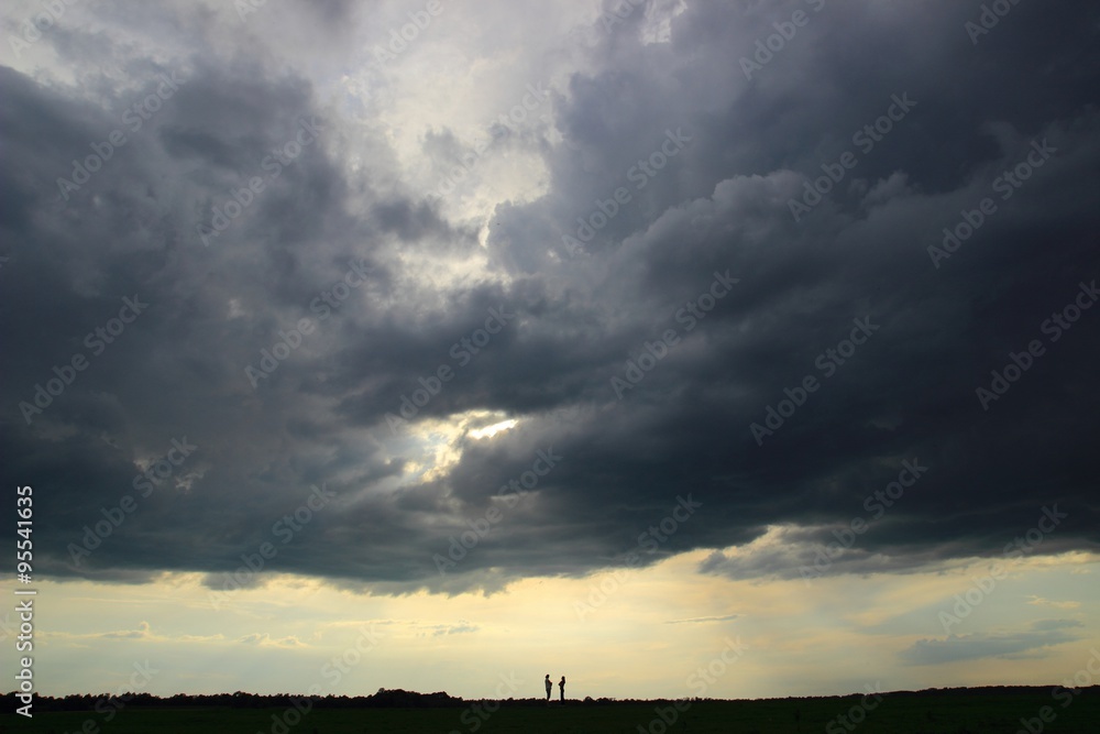 Silhouettes of two persons in conversation under storm cloud Silhouettes of two persons in conversation under storm cloud