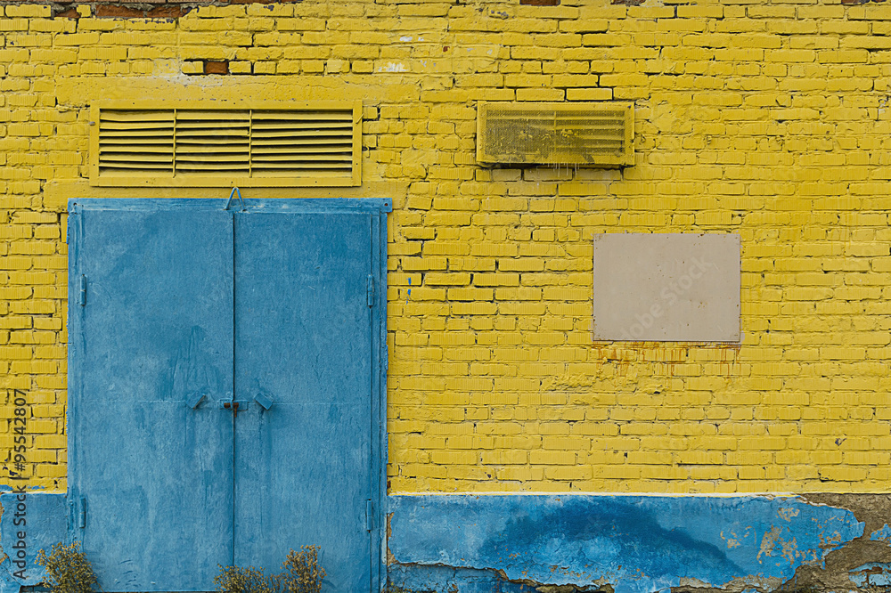 Naklejka premium yellow brick wall with blue door