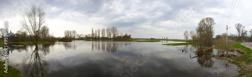 Spring flood with sky reflections and stormy weather. Panorama.
