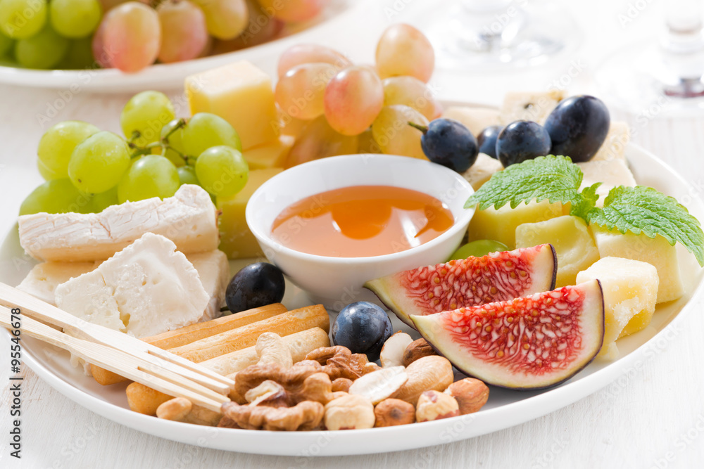 cheeses, fresh fruits, wine and snacks on plate cheeses, fresh fruits, wine and snacks on plate
