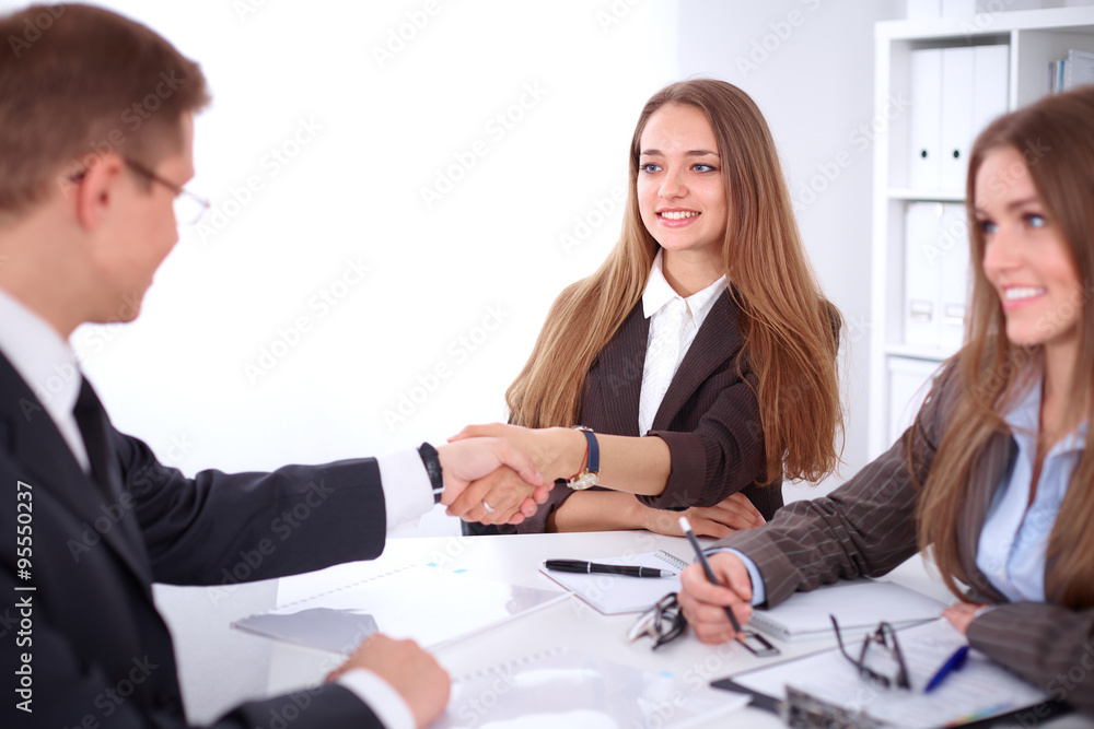 Business handshak sitting at the desk on office background, copy space area at the left upper corner Business handshak sitting at the desk on office background, copy space area at the left upper corner