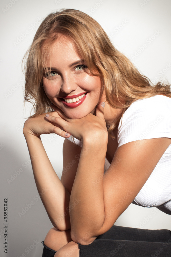 Awesome caucasian attractive sexy professional female model with blond hair posing in studio wearing white shirt and black ripped jeans, smiling, isolated on white background Awesome caucasian attractive sexy professional female model with blond hair posing in studio wearing white shirt and black ripped jeans, smiling, isolated on white background