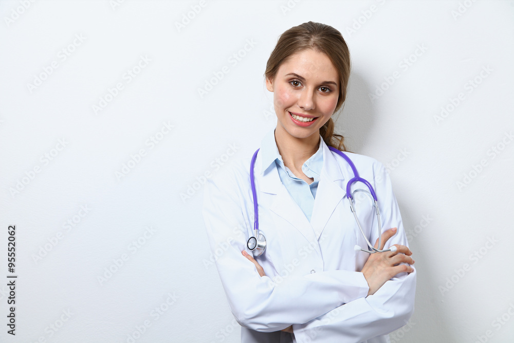 Friendly smiling young female doctor, standing near wall Friendly smiling young female doctor, standing near wall