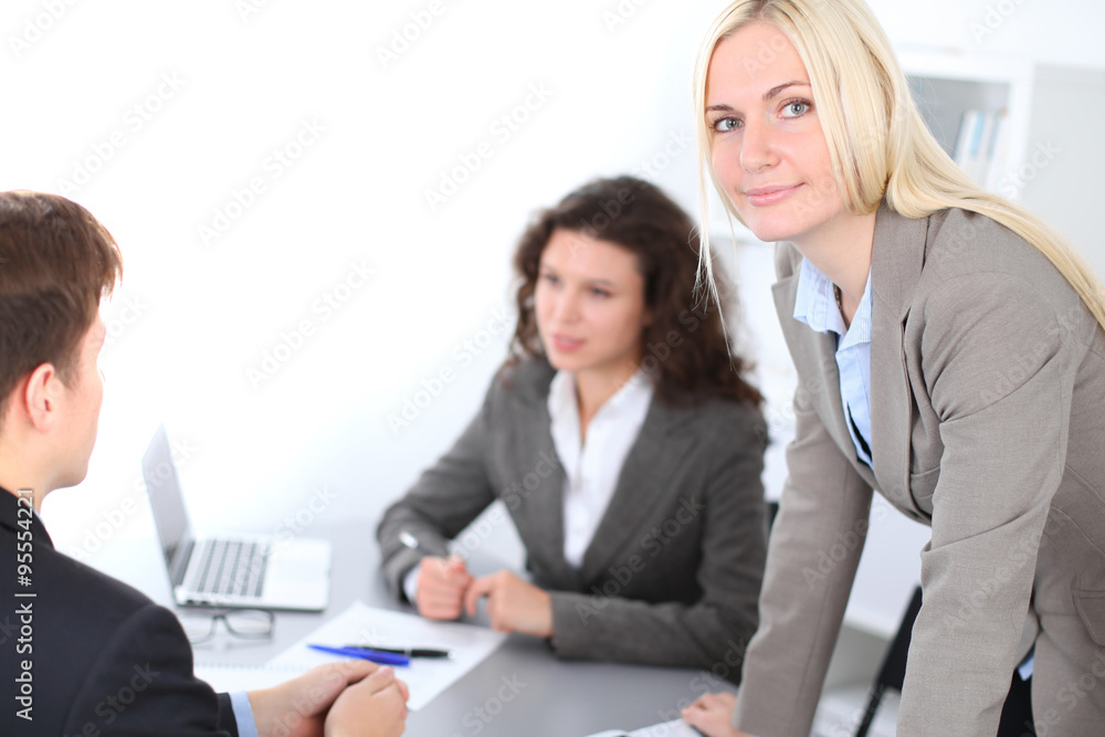 A group of business people at a meeting on the background of office. Focus on a beautiful blonde A group of business people at a meeting on the background of office. Focus on a beautiful blonde