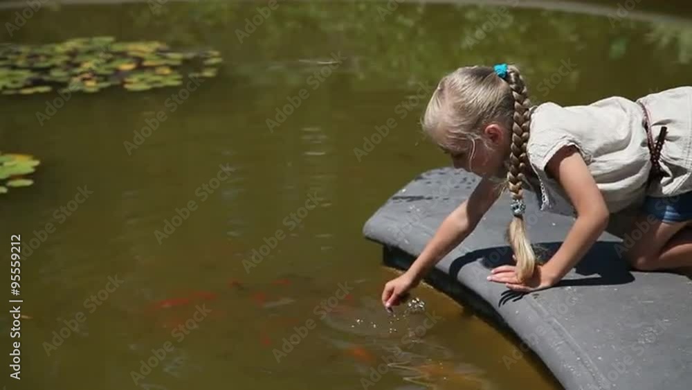 Little girl playing with a fish which living in a pond Little girl playing with a fish which living in a pond