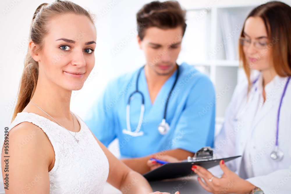 Happy blond female patient next to a few doctors in hospital sitting at the table Happy blond female patient next to a few doctors in hospital sitting at the table